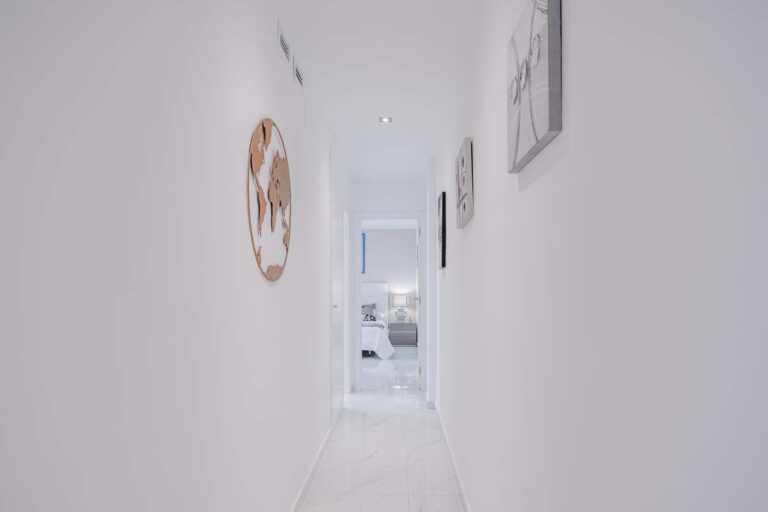 Bright hallway inside a renovated apartment in Arenal-Bol, Calpe with white walls and access to bedrooms and bathrooms