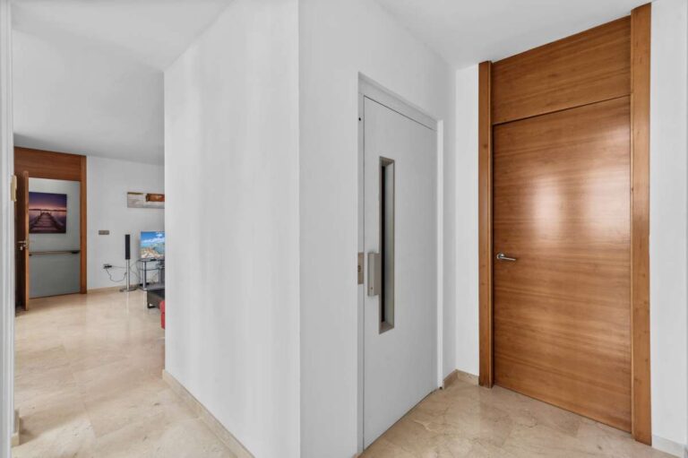 Bright interior hallway with wooden entrance door inside a modern spacious villa in Calpe.
