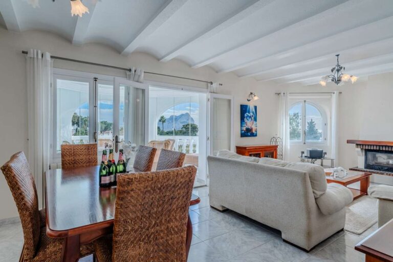 Bright living and dining area with fireplace and traditional furniture inside a Mediterranean villa in Calpe.