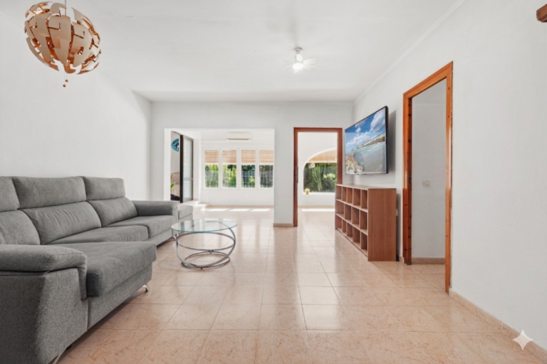 Bright living room inside a Mediterranean villa in Benissa Costa near Cala Baladrar with sofa, TV area and terrace access