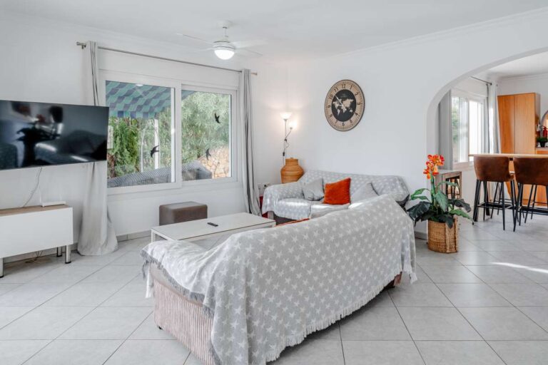 Bright living room inside a villa in Calpe with sofa seating, TV and large window