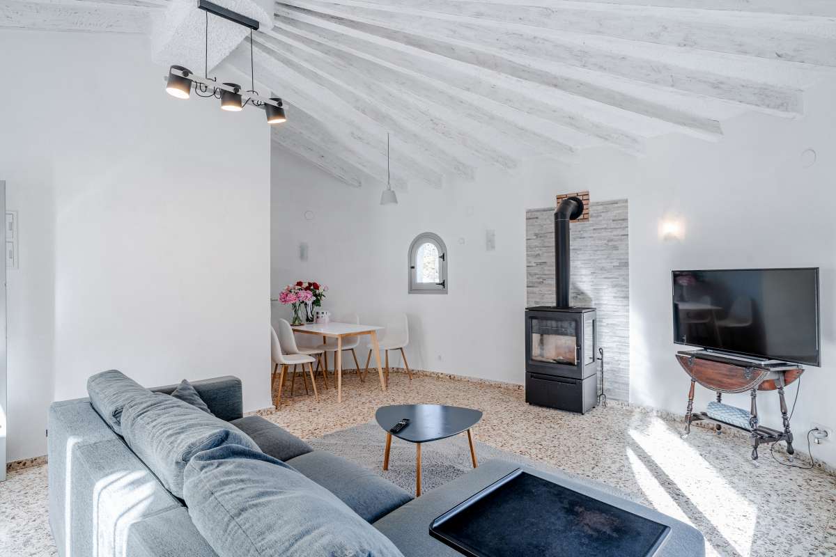 Bright living room with sofa, fireplace, arched window and beamed ceiling inside a Mediterranean villa in Maryvilla, Calpe.