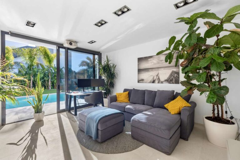 Bright living room with sofa, large windows and garden views inside a modern oasis villa in Calpe.