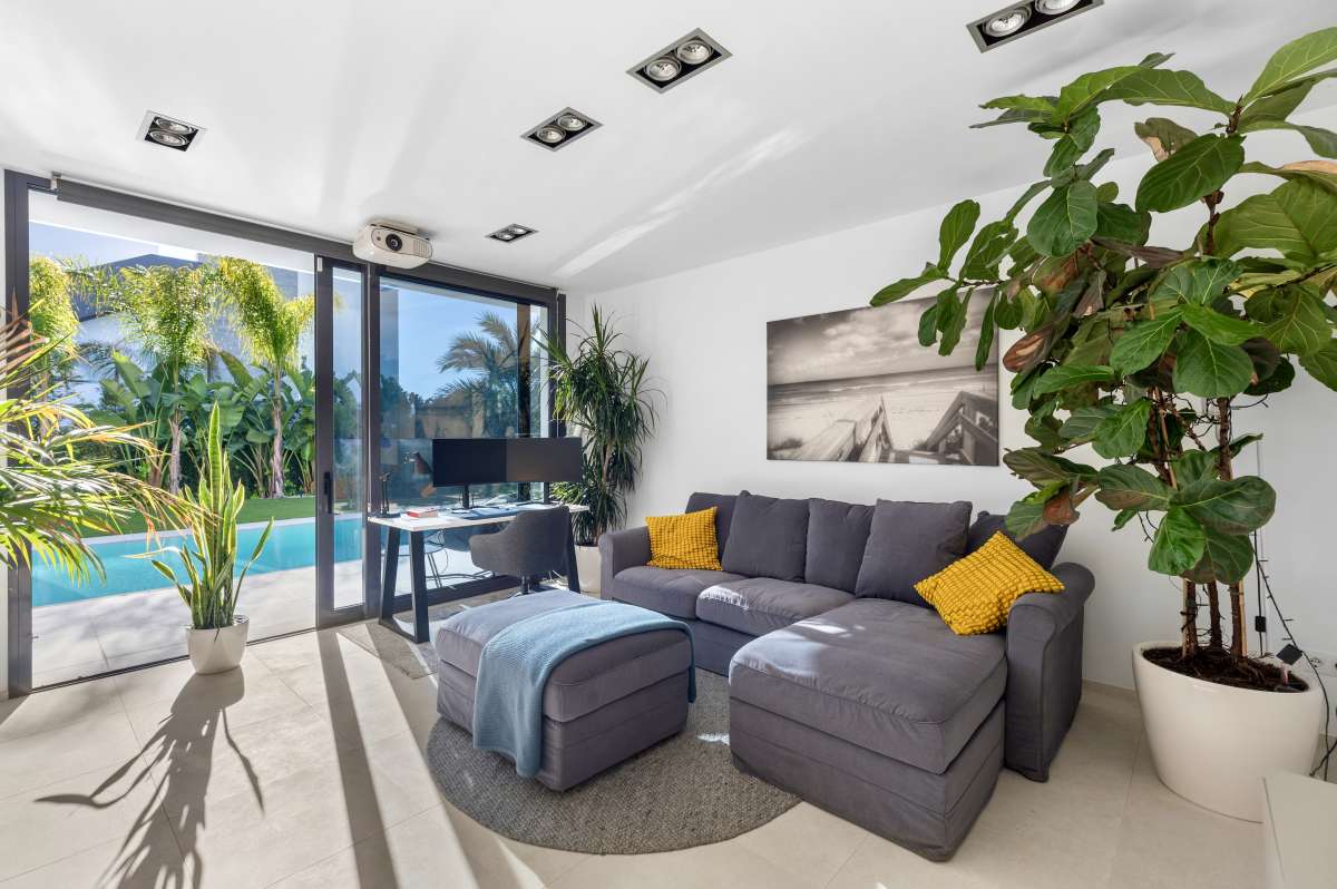 Bright living room with sofa, large windows and garden views inside a modern oasis villa in Calpe.