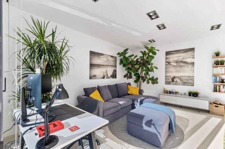 Bright living room with sofa, workspace and garden views inside a modern oasis villa in Calpe.