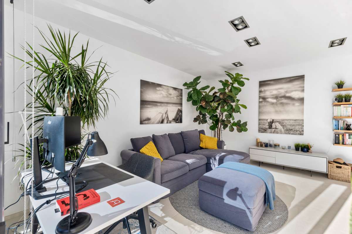 Bright living room with sofa, workspace and garden views inside a modern oasis villa in Calpe.