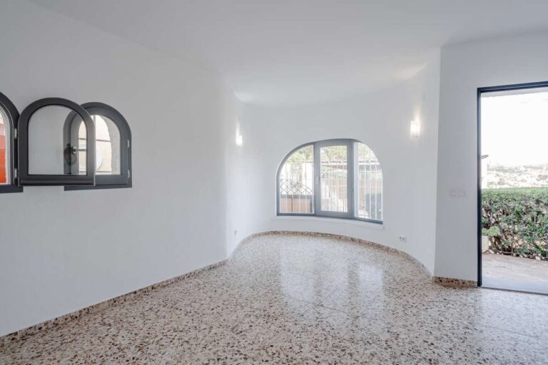 Bright living space with arched window, tiled flooring and terrace access inside a Mediterranean villa in Maryvilla, Calpe.