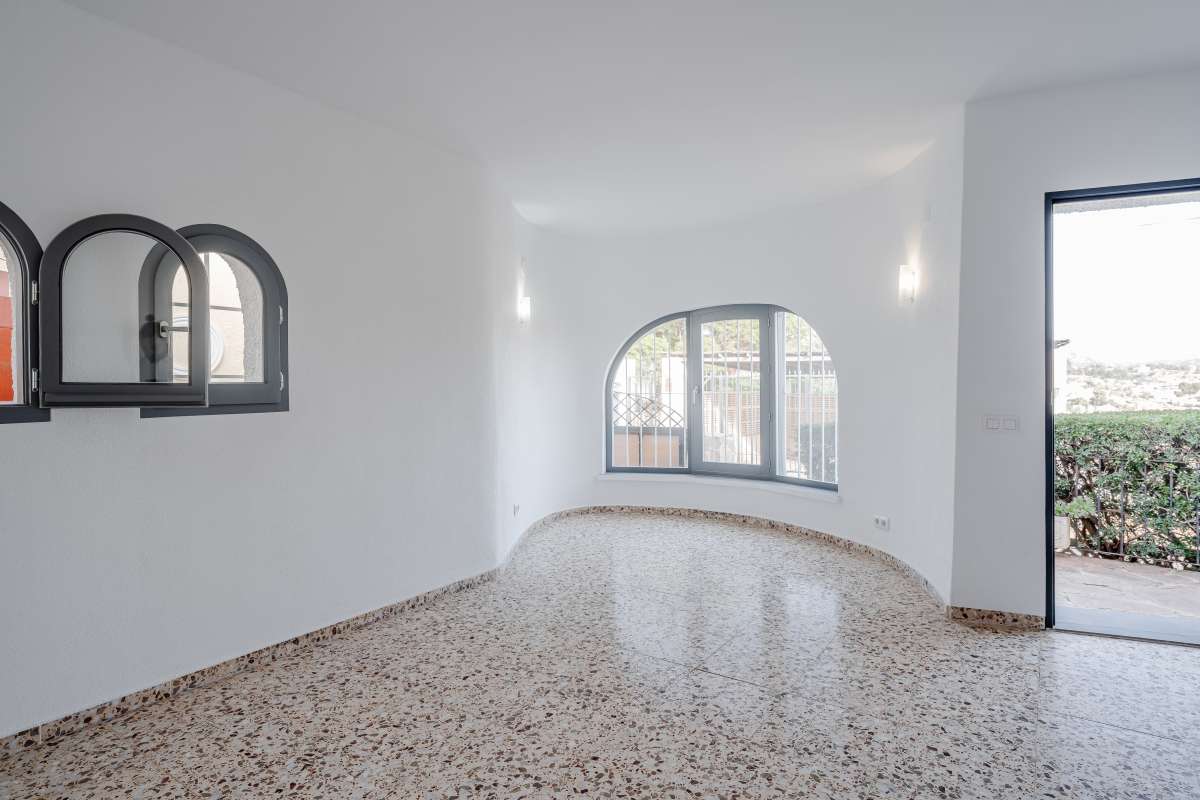 Bright living space with arched window, tiled flooring and terrace access inside a Mediterranean villa in Maryvilla, Calpe.
