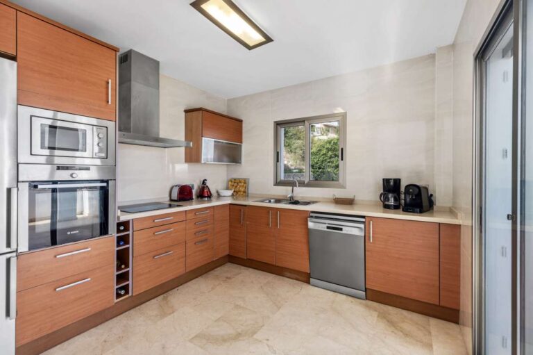 Closed fitted kitchen with wooden cabinets and modern appliances inside a spacious villa in Calpe.