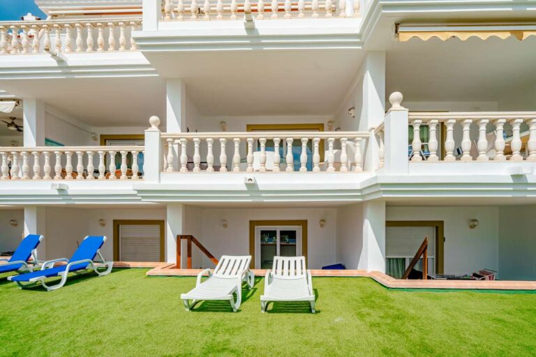 Communal gardens at a duplex apartment near Les Platgetes Beach in Moraira with apartment terraces, sun loungers and landscaped lawn area