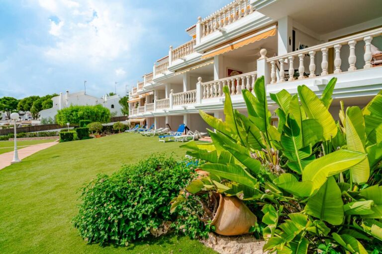 Communal gardens at a duplex apartment near Les Platgetes Beach in Moraira with landscaped lawn, tropical planting, apartment terraces and sun loungers