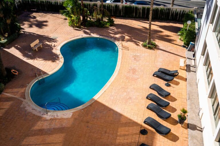 Communal swimming pool at a beachfront apartment building by La Fossa Beach in Calpe with sun loungers and terrace area