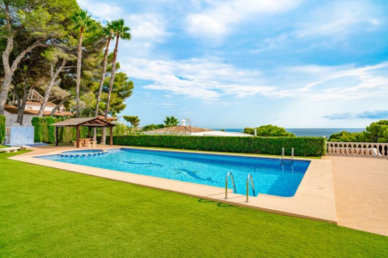 Communal swimming pool at a duplex apartment near Les Platgetes Beach in Moraira with landscaped gardens, sun terrace and sea views beyond