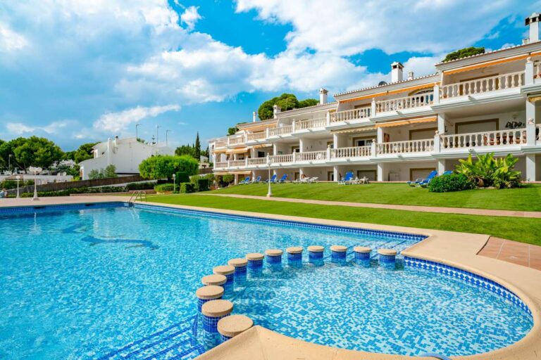 Communal swimming pool at a duplex apartment near Les Platgetes Beach in Moraira with landscaped gardens, sunbathing areas and residential complex