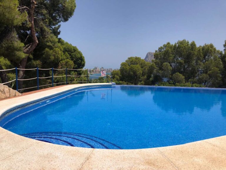 Communal swimming pool at a frontline townhouse complex in Calpe with sea views and Mediterranean trees