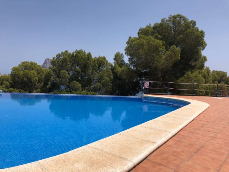 Communal swimming pool at a frontline townhouse complex in Partida Manzanera, Calpe with Mediterranean trees