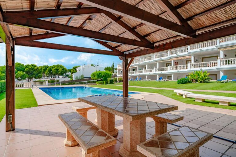 Communal terrace at a duplex apartment near Les Platgetes Beach in Moraira with covered outdoor dining area, swimming pool and landscaped gardens