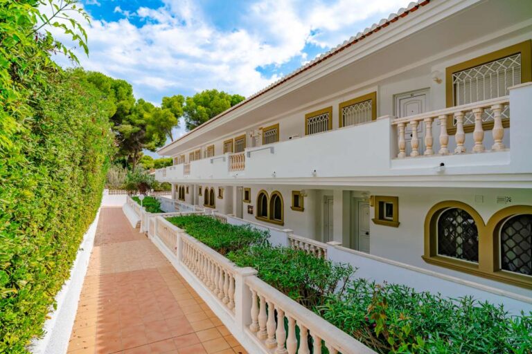 Communal walkway at a duplex apartment near Les Platgetes Beach in Moraira with white balustrade, landscaped planting and apartment exterior