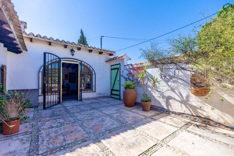 Courtyard access at a traditional Spanish finca near Moraira with arched doors, tiled terrace, potted plants and rustic Mediterranean exterior