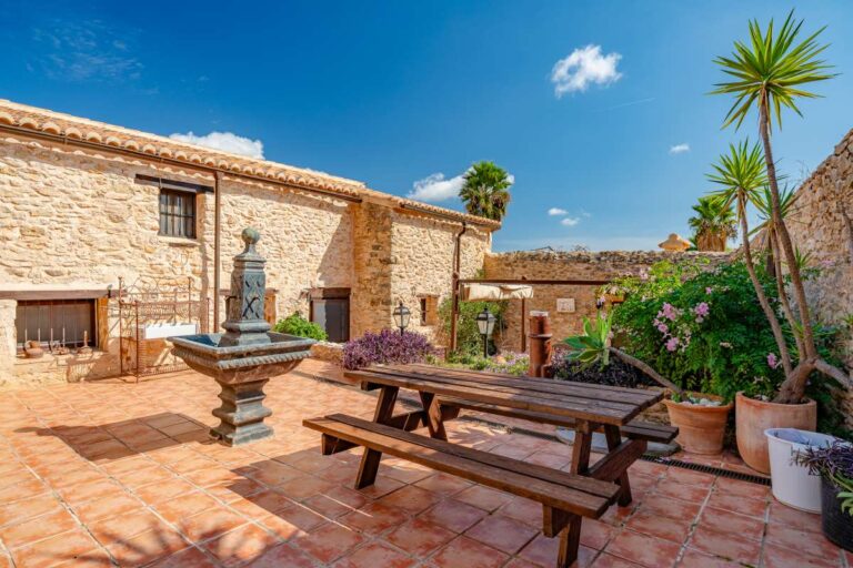 Courtyard at a historic finca in Benissa with stone walls, traditional fountain, outdoor seating and Mediterranean planting