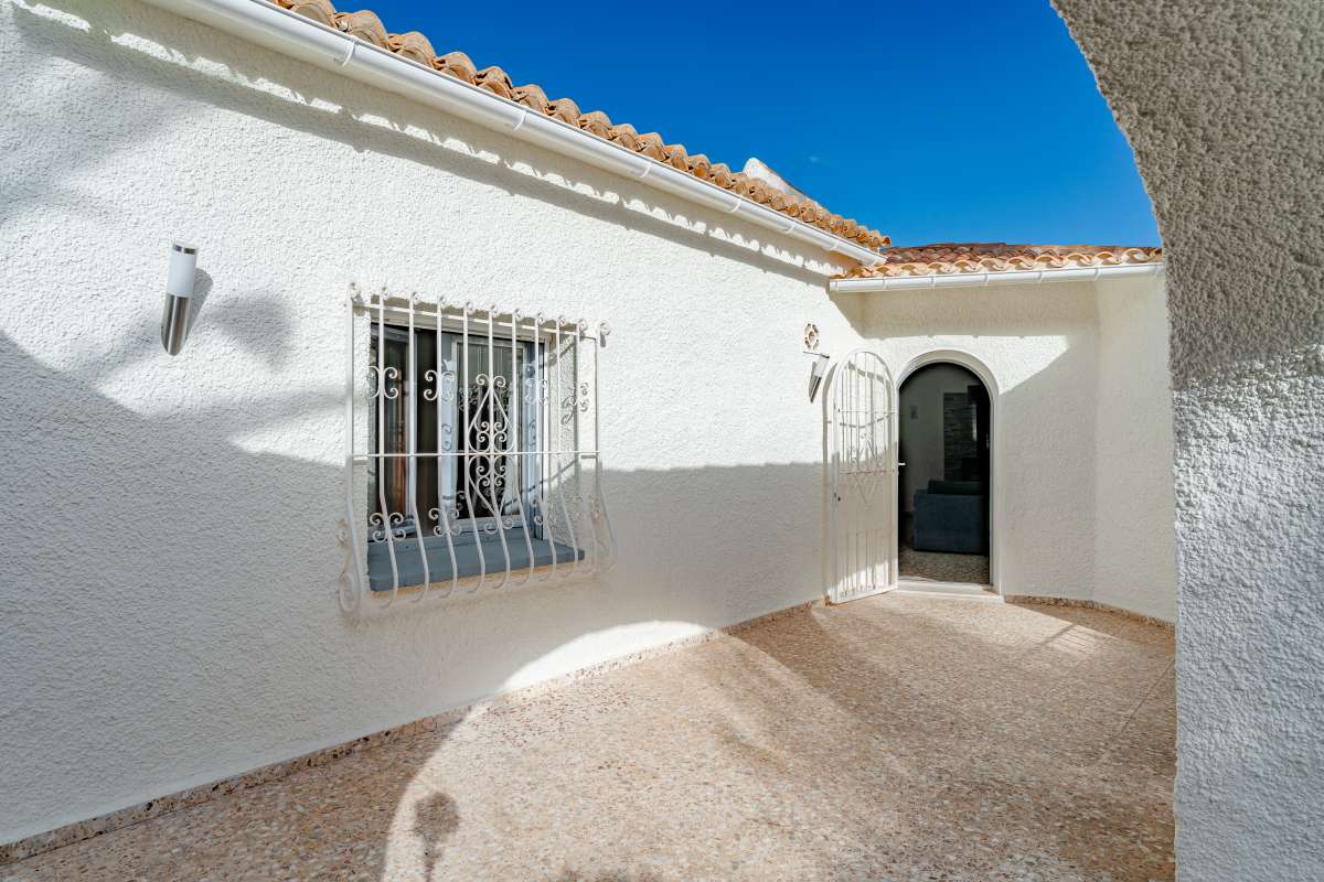 Courtyard entrance with traditional white exterior and arched doorway at a Mediterranean villa in Maryvilla, Calpe.
