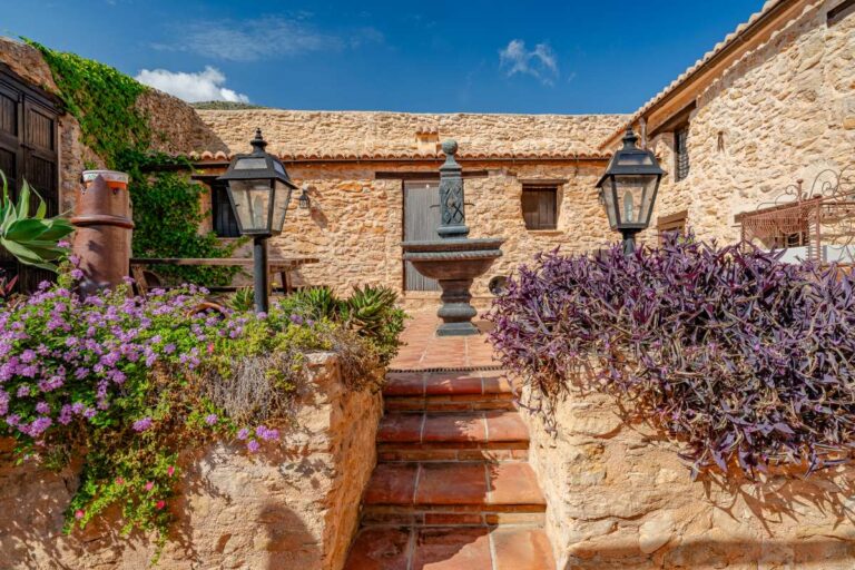 Courtyard garden at a historic finca in Benissa with stone walls, traditional steps, Mediterranean plants and rustic architectural details