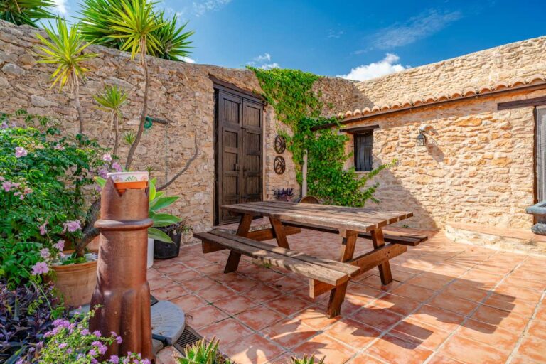 Courtyard seating area at a historic luxury finca in Benissa with stone walls, wooden table, Mediterranean plants and traditional character