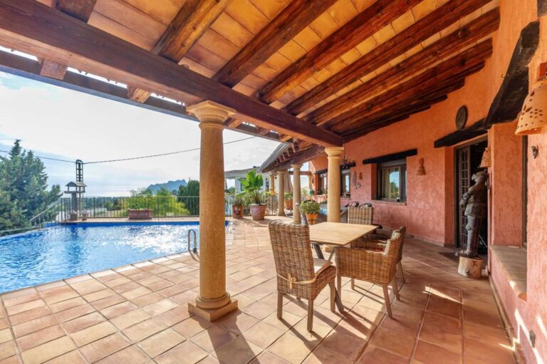 Covered dining terrace at a finca-style villa in Benissa Costa with wooden beams, outdoor dining table, infinity pool views and sea views