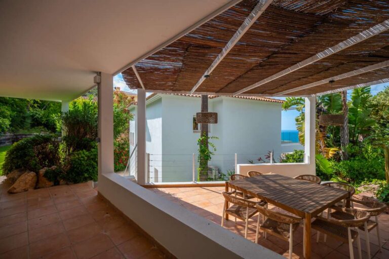 Covered dining terrace at a modern villa in Altea Hills with outdoor table, shaded pergola, garden views and partial sea views