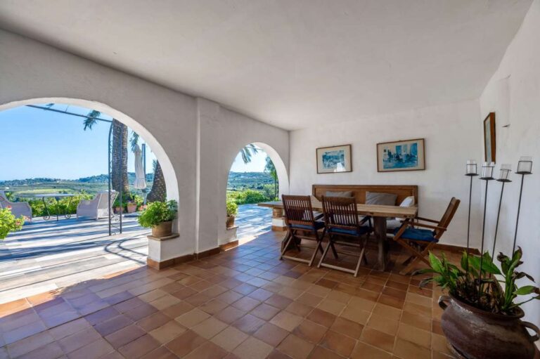 Covered dining terrace at a traditional Spanish finca near Moraira with arched openings, outdoor dining table, tiled floor and countryside views