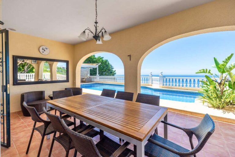 Covered dining terrace at an Altea Hills villa with outdoor table, arched openings, private pool views and panoramic sea views