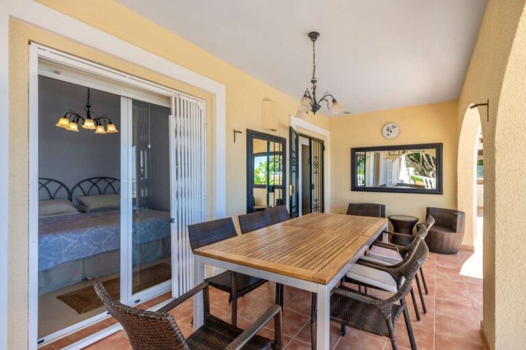 Covered dining terrace at an elegant Mediterranean villa in Altea Hills with outdoor table, bedroom access and shaded seating area