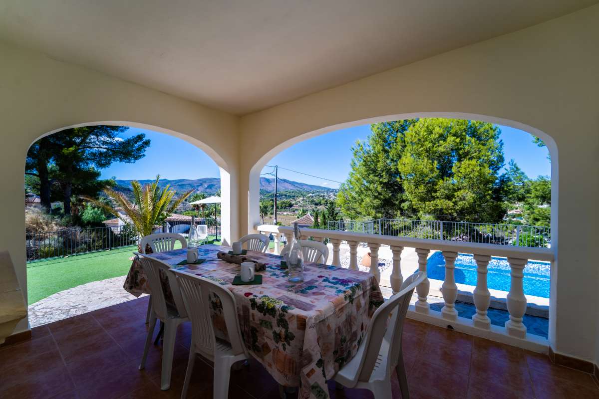 Covered dining terrace with garden and mountain views at a Mediterranean villa in Calpe.