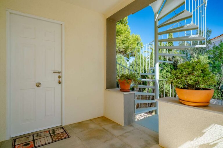 Covered entrance terrace at a modern villa in Calpe with exterior stairs, potted plants and Mediterranean surroundings