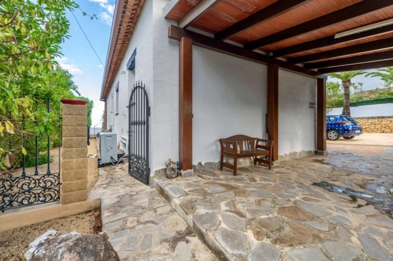 Covered entrance terrace at a premium coastal villa on the Benissa Costa with timber pergola, stone paving and garden surroundings