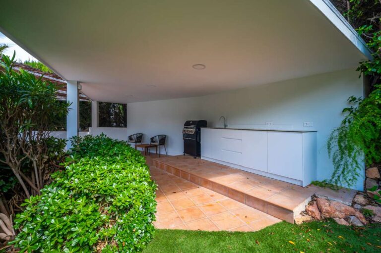 Covered outdoor area at a modern villa in Altea Hills with garden views, storage area, tiled terrace and Mediterranean planting