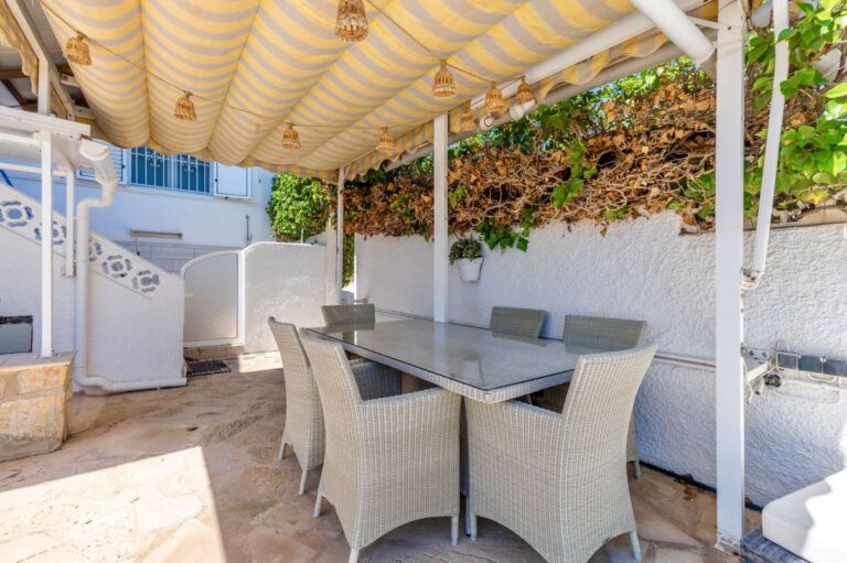 Covered outdoor dining area at a renovated single-level villa in Moraira with pergola, dining table, built-in seating and shaded terrace space