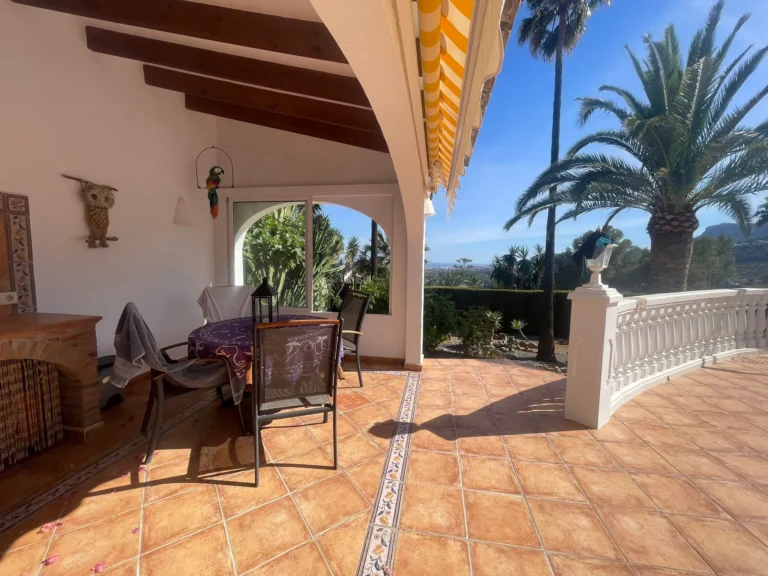 Covered outdoor dining terrace with tiled floor and garden views at a villa in Calpe.