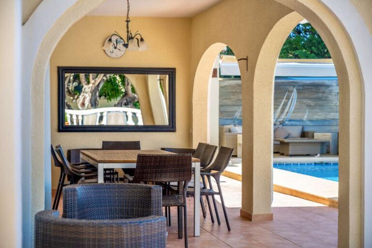 Covered outdoor living area at an elegant Mediterranean villa in Altea Hills with dining space, lounge seating and pool terrace access