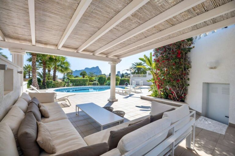 Covered outdoor seating area with sofa and terrace space at a villa in Calpe.