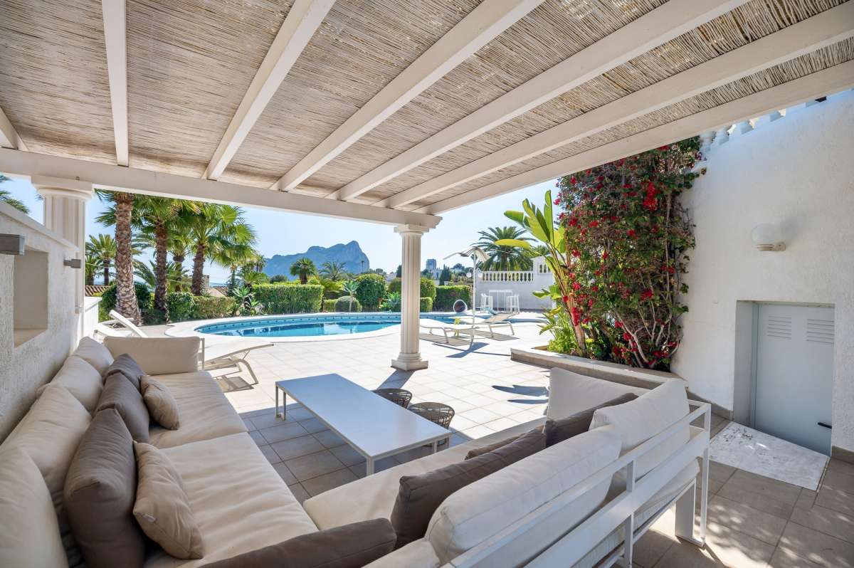 Covered outdoor seating area with sofa and terrace space at a villa in Calpe.