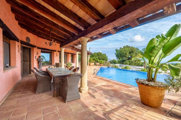 Covered pool terrace at a finca-style villa in Benissa Costa with wooden beams, outdoor seating, infinity pool and sea views
