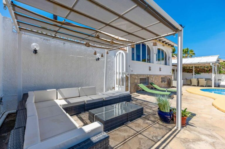 Covered poolside lounge at a renovated single-level villa in Moraira with outdoor seating, pergola, stone terrace and pool access