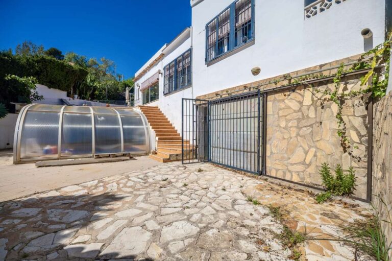 Covered swimming pool and garage exterior at a Mediterranean villa in Benissa Costa near Cala Baladrar with stone driveway and terrace access