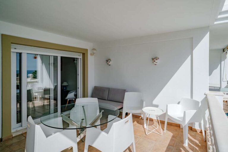 Covered terrace at a duplex apartment near Les Platgetes Beach in Moraira with outdoor dining area, sliding doors and bright sheltered seating space