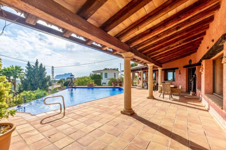 Covered terrace at a finca-style villa in Benissa Costa with wooden beams, infinity pool, sea views and outdoor dining area