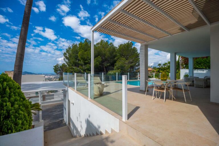 Covered terrace at a modern villa in Altea Hills with outdoor dining area, glass railing, private pool and sea views
