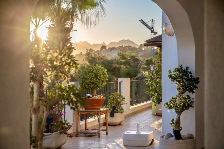 Covered terrace at a panoramic sea view villa in Benissa with Mediterranean plants, outdoor seating and mountain views at sunset