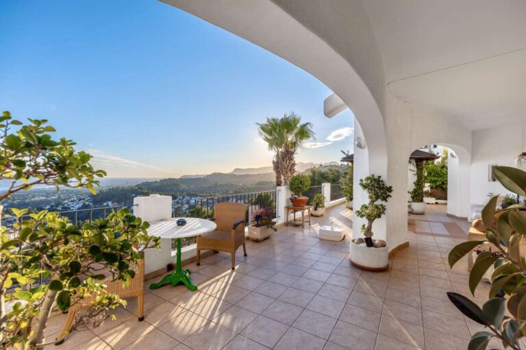 Covered terrace at a panoramic sea view villa in Benissa with outdoor seating, Mediterranean plants and open valley views