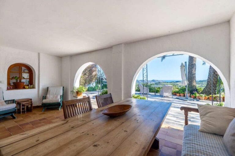 Covered terrace at a traditional Spanish finca near Moraira with wooden table, arched opening, outdoor seating and countryside views